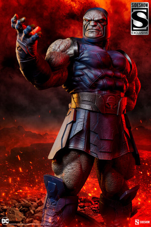 Darkseid DC Comics Maquette from Sideshow Collectibles. A detailed figure of a comic book character with a stony appearance stands with a menacing pose against a fiery red and orange backdrop, with embers floating around.