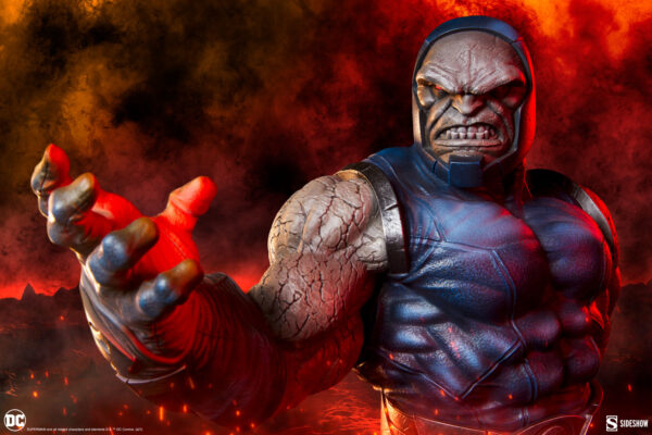 Darkseid DC Comics Maquette from Sideshow Collectibles. A figurine of a muscular superhero with a stern expression, reaching forward, set against a dramatic background of dark clouds and red flames.