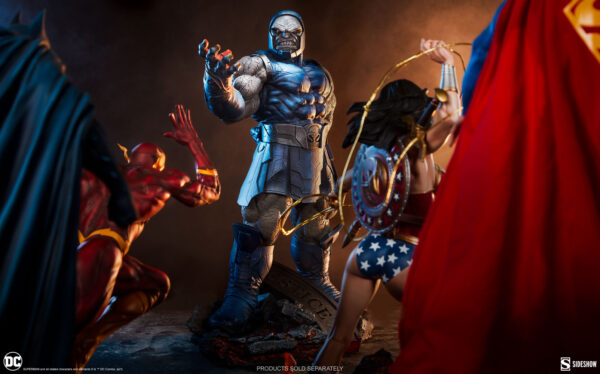 Darkseid DC Comics Maquette from Sideshow Collectibles. Statues of comic book characters, prominently featuring a dark-clad figure in the center with two other characters in red and golden attire partially visible from the side views.