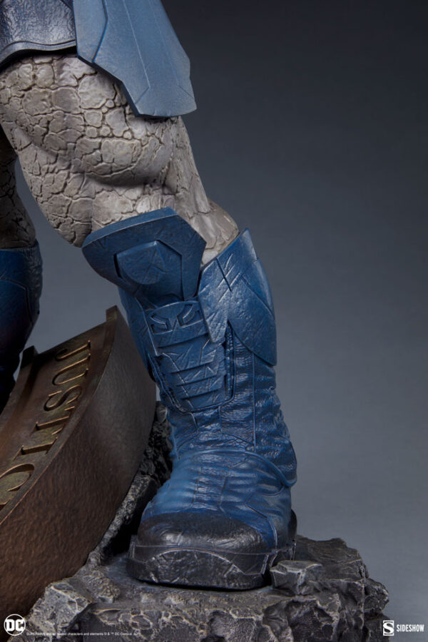 Darkseid DC Comics Maquette from Sideshow Collectibles. A detailed view of a superhero statue's leg, showcasing textured skin and blue armored costume on a rocky base.