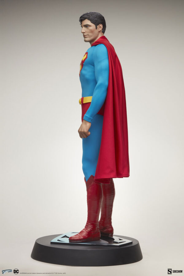 Superman: The Movie Premium Format™ Figure from Sideshow Collectibles and DC Comics. Side view of a Superman statue on a stand, showcasing the classic blue costume with red cape and boots.