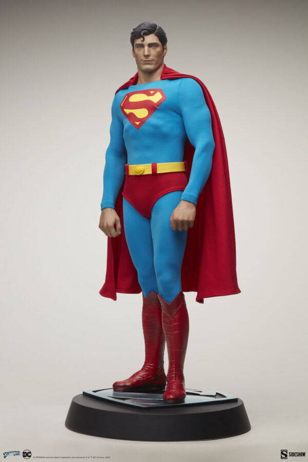 Superman: The Movie Premium Format™ Figure from Sideshow Collectibles and DC Comics. A collectible figurine of Superman standing heroically on a black base, wearing his iconic blue costume with the red cape, red boots, and the famous 'S' logo on his chest.