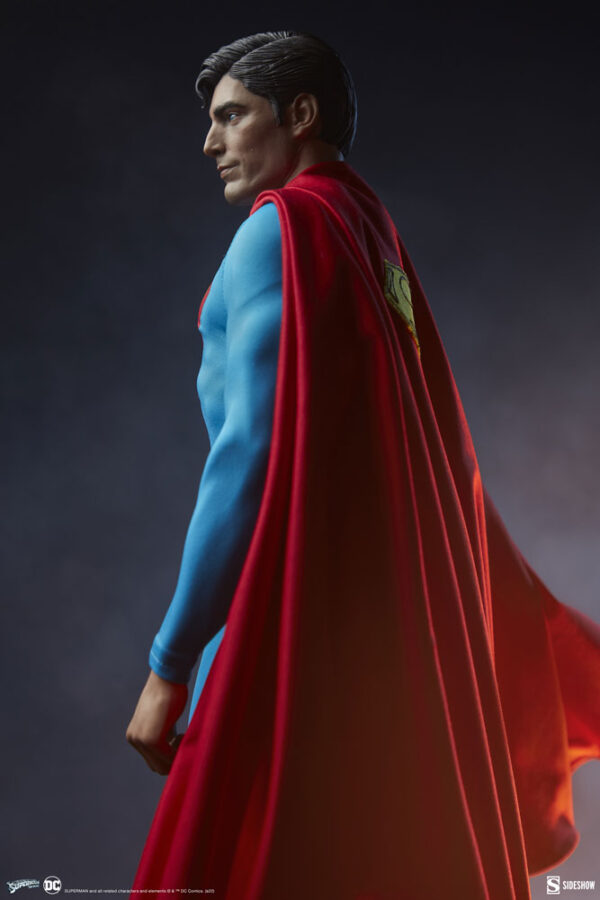 Superman: The Movie Premium Format™ Figure from Sideshow Collectibles and DC Comics. A detailed figure of a superhero with a blue suit and big red cape looking into the distance against a dark background.