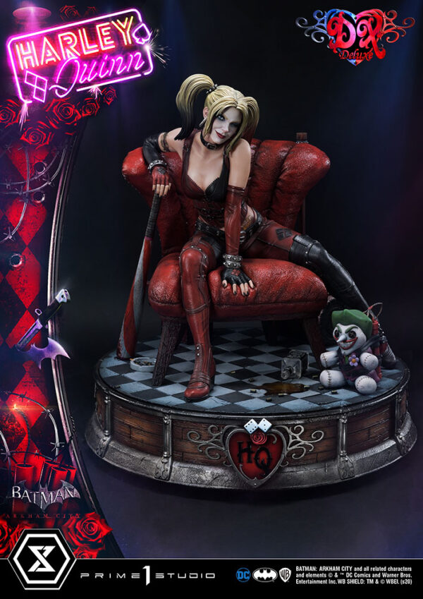 Harley Quinn Deluxe Batman Arkham City Statue Deluxe Version 1:3 Scale Statue from DC Comics and Prime 1 Studio. A collectible figurine of Harley Quinn seated on a red chair with a bat, accompanied by a small jester doll, against a background with themed graphics and logos.