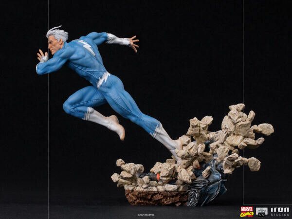 Marvel Quicksilver 1:10 scale statue from Iron Studios. A collectible figure of a superhero with white hair and blue suit, mid-jump above a rocky debris explosion base, against a black background.