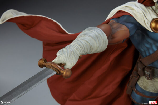 Marvel Taskmaster Premium Format Figure from Sideshow Collectibles. Close-up of a superhero figure's hand drawing a sword, with flowing red cape in the background.