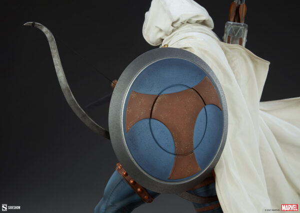 Marvel Taskmaster Premium Format Figure from Sideshow Collectibles. A detailed view of a superhero costume featuring a shield with a star emblem and a bow in the background with a cape and quiver.