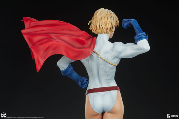 Power Girl Premium Format™ Figure from Sideshow Collectibles. A detailed statue of a female superhero with flowing red cape, white costume, and blue gloves from the back view showing a muscular pose.