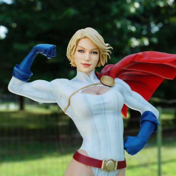 Power Girl Premium Format™ Figure from Sideshow Collectibles. A collectible figurine of a female superhero with blonde hair, designed with a red cape, blue gloves, and a confident pose, set against a blurred green background.