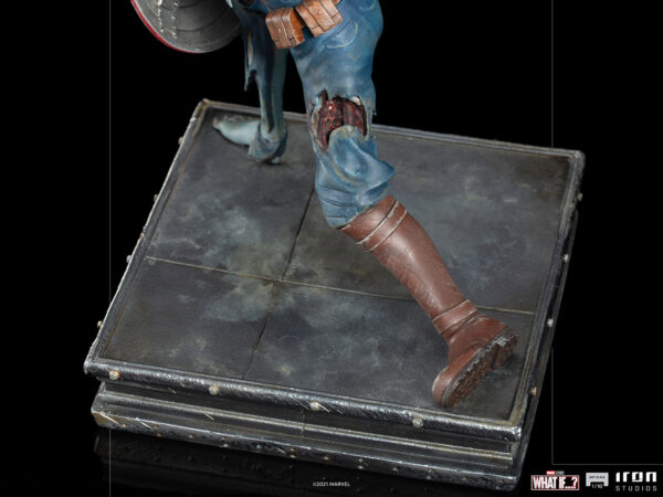 Zombie Captain America Art Scale 1:10 Statue. Zombie Captain America statue in a crouched pose, holding his iconic shield in a defensive stance. His skin appears decayed and blue-toned, with exposed muscles and torn uniform, embodying a grotesque and undead version of the classic Marvel superhero. The statue is set on a rugged, metallic base.