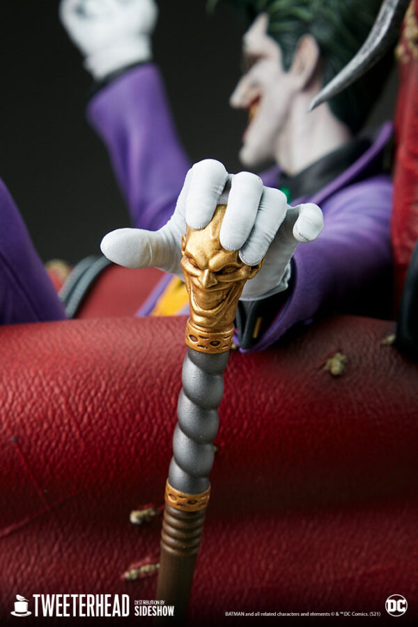 The Joker Deluxe Collector Edition Maquette from DC Comics and Tweeterhead. Close-up image of a hand wearing a white glove holding a golden cane, with the Joker figure blurred in the background.