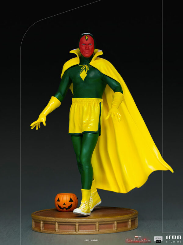 Vision Halloween Version WandaVision Art Scale 1:10 Statue from Marvel and Iron Studios. A collectible statue of a classic superhero in green and yellow costume with a cape, standing next to a small Halloween pumpkin on a wooden base.