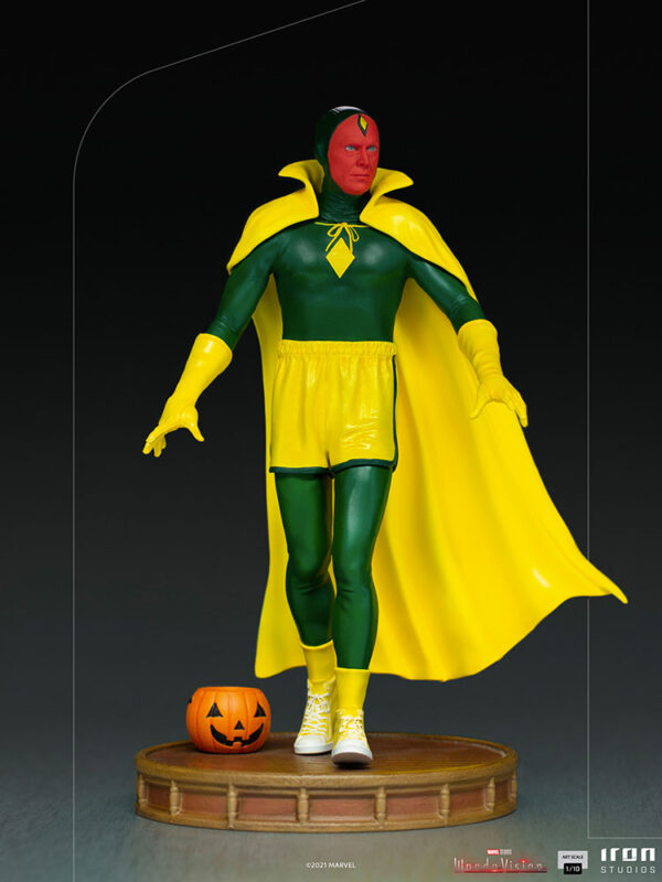 Vision Halloween Version WandaVision Art Scale 1:10 Statue from Marvel and Iron Studios. A collectible statue of the character Vision dressed in his classic green and yellow superhero costume standing next to a jack-o'-lantern on a wooden base.